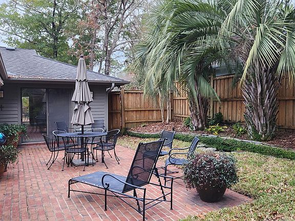 Fenced yard and brick patio and with mature landscaping and furniture