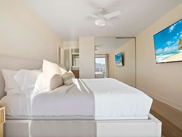 Spacious bedroom with a king-size bed, mirrored closet, and calming beach-inspired decor.