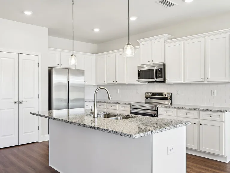 Sleek kitchen with white cabinetry and granite countertops.