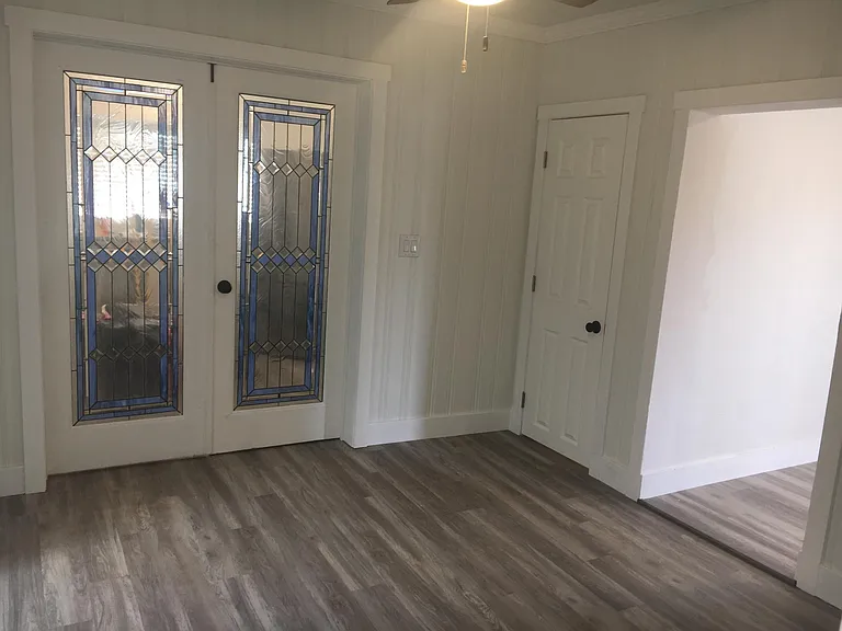 Common room looking at stained glass doors to kitchen, other door goes to basement. Other passageway goes to living room.