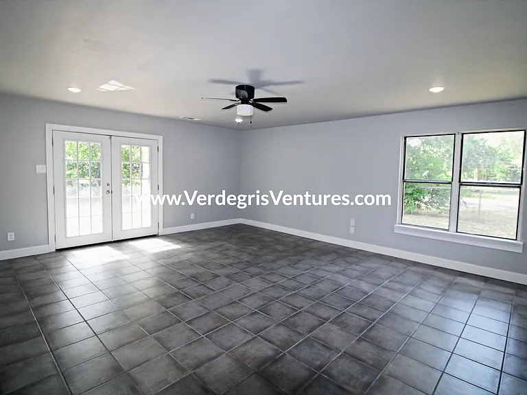 The living room is exceptionally spacious and sits at the front entrance, opening through double French doors. Abundant natural light flows in from both the east and south exposures