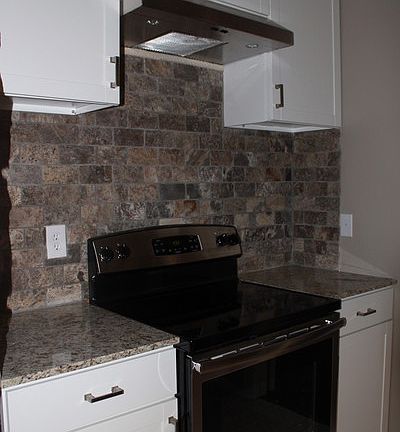 Alternative view of kitchen
						:
						Natural stone backsplash, stainless steel electric range, granite counter