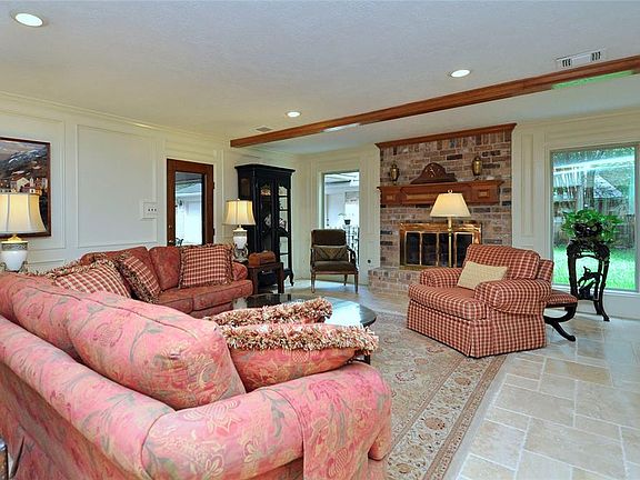 Welcome to this comfortable family room. Notice the upgraded travertine floor, the full length back windows, wood-burning fireplace, canned lights, door to back patio and popular painted wood paneling.