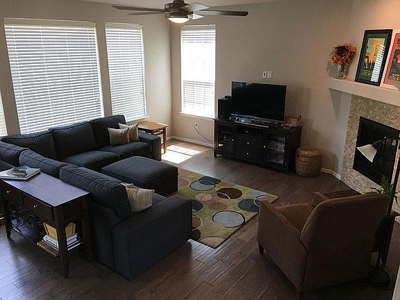 Spacious open floor plan with gas fireplace and ceiling fan.