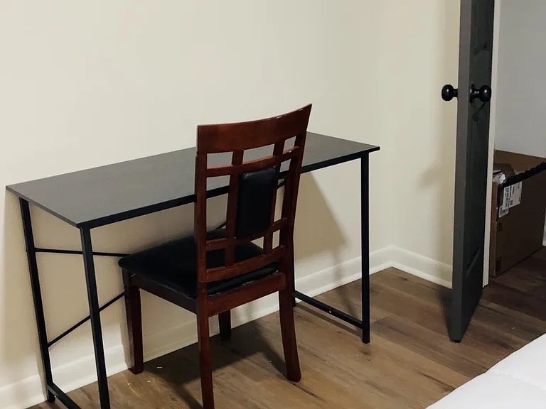 Bedroom workspace nook with a dedicated desk and chair, wood-style floors, and convenient closet access for storage.