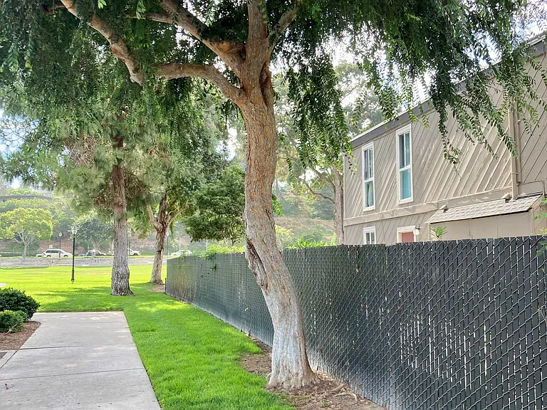 Tree lined park walkway just outside of parking lot at Solana Park Apartments in Solana Beach, California.