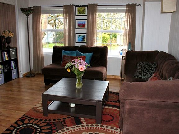 the warm and inviting living room features beautiful floors, tung and groove wood work and ample sunlight through the new vinyl windows.