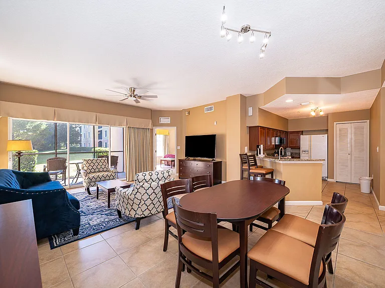 Open-concept living and dining area with seating, TV space, and breakfast bar connecting to the kitchen and patio access.