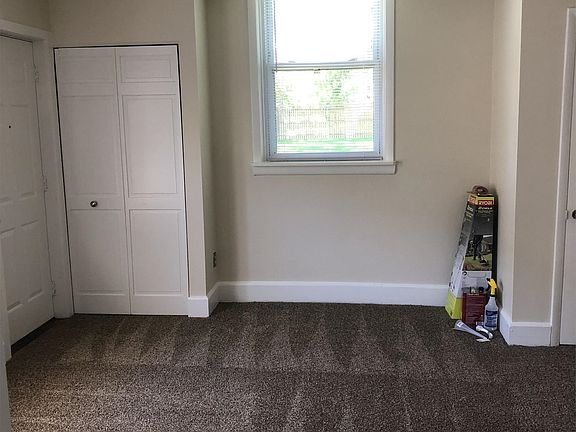 There is a large bedroom with several big windows and a door leading to the backyard/driveway.