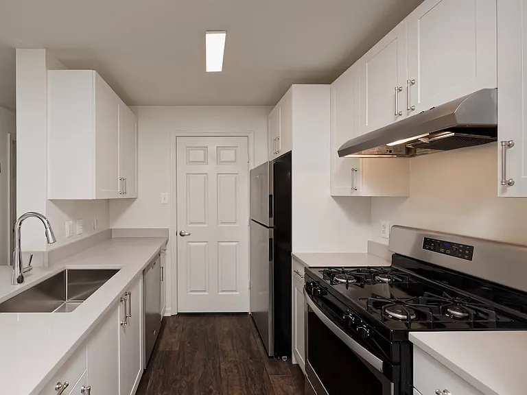 Renovated Package II kitchen with light grey quartz countertops, white cabinetry, stainless steel appliances, and hard surface flooring
