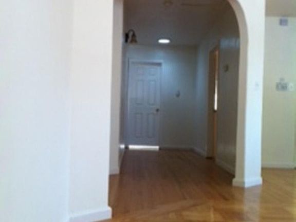View of hallway from living room, with full bath at the end, and bedrooms on the left