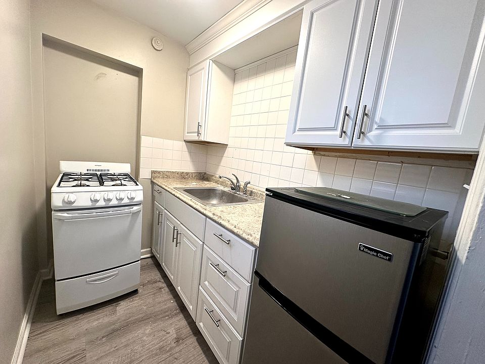 Charming compact kitchen with modern appliances, sleek white cabinetry, and stylish countertops.