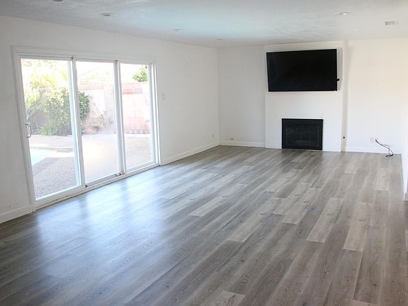 Spacious living room with sliding doors to pool and yard, TV above fireplace.