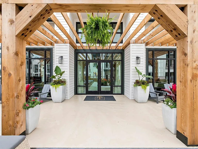 Resort-style apartment patio with pergola, poolside seating, and lush landscaped outdoor gathering spaces.