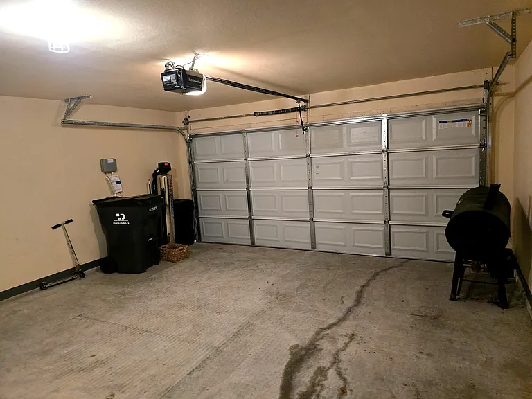 Attached finished 2-car garage with ample space for parking, storage, home gym, and workspace.