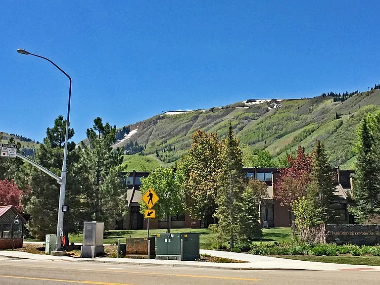 The entrance to the Park Ave. Condos with a bus stop on the left and the Park City ski slopes in the background.