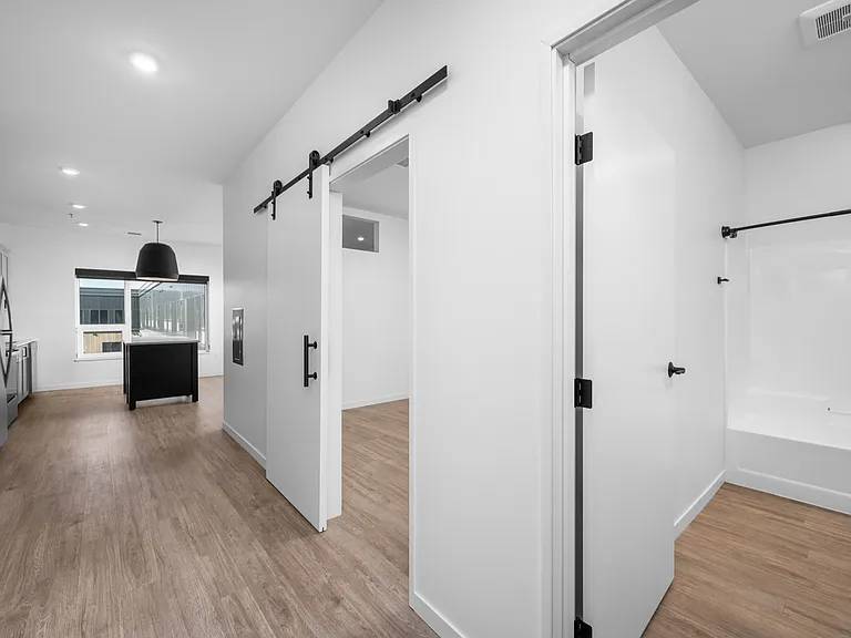 Modern apartment interior showcasing sleek kitchen, sliding barn doors, and pristine bathroom with stylish design. Modern apartment interior showcasing sleek kitchen, sliding barn doors, and pristine bathroom with stylish design.