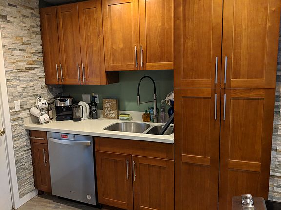 Kitchen sink and dishwasher with overhead cabinets.