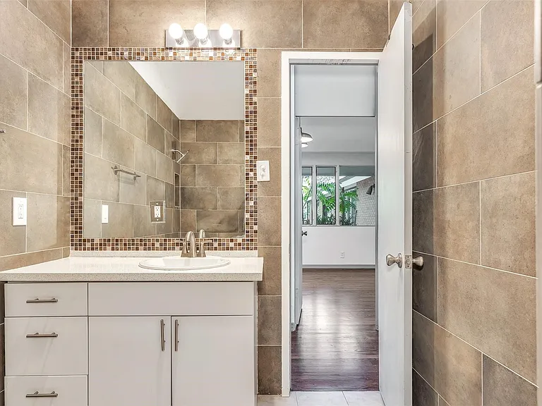 Bathroom vanity featuring a single basin, light-toned countertop, and white cabinetry with brushed nickel hardware