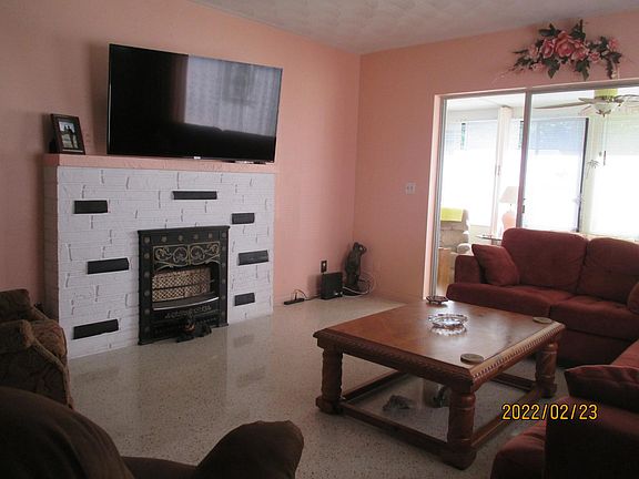 Living room with wall mounted tv over fireplace. Terrazzo floors. Sliding doors go to 10x30 Florida room.