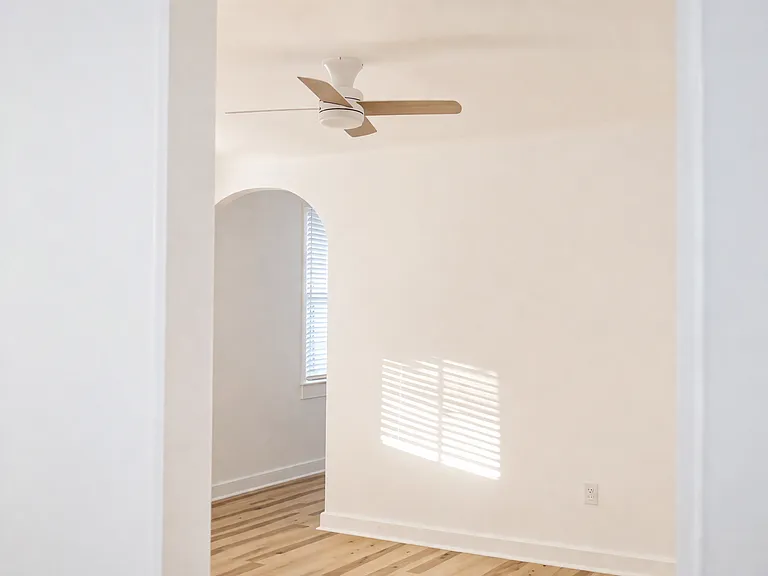 Light-filled living area featuring wood-style flooring, an arched hallway opening, and seamless flow between rooms