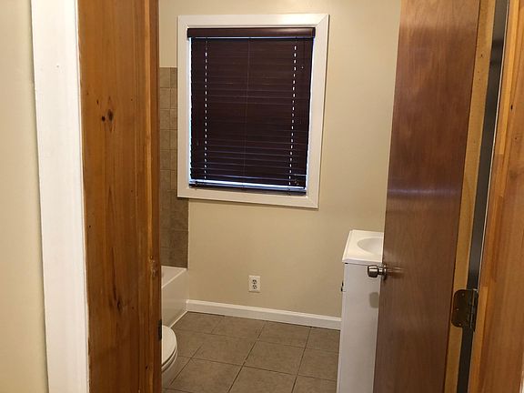 Bathroom: (1) toilet, (1) vanity, (1) window, bathtub with shower head