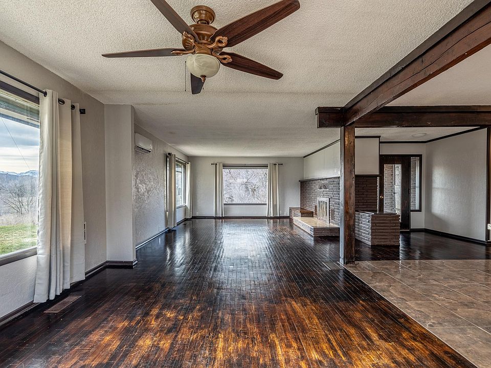 Large windows overlooking Cascade Mountains, open dining room, living room with wood fireplace, and large kitchen.