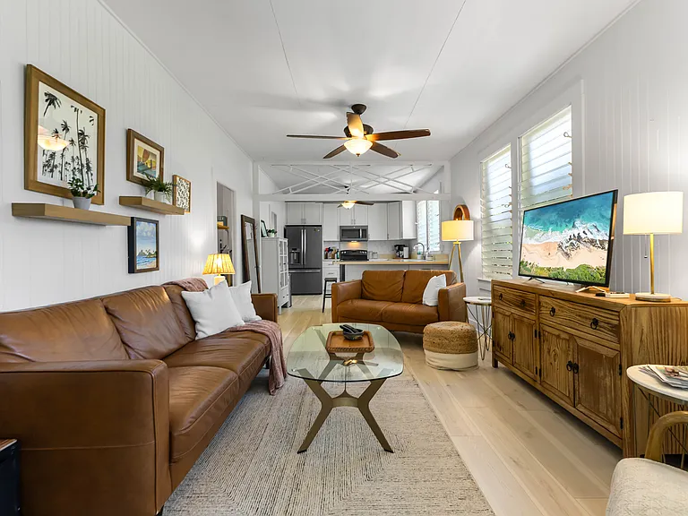 The living room includes an Italian leather sofa and loveseat and one chair, TV, ceiling fan, windows and an AC unit. The living room opens to the lanai and blends seamlessly with the kitchen.