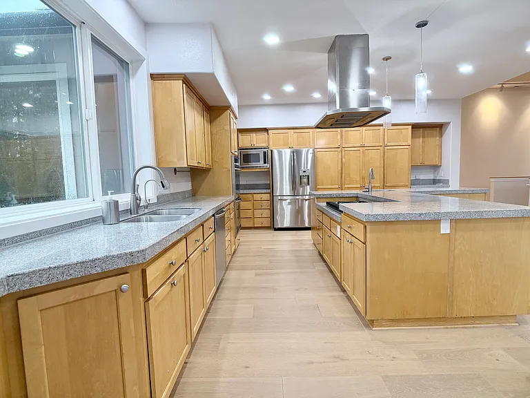 Expansive chef's kitchen with exceptional storage, featuring dual sinks with disposals, a professional-grade six-burner gas range, a large double oven, and an island with seating for 2_3.