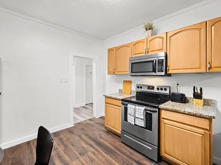 Efficient kitchen with ample wood cabinetry, stone-look counters, and stainless-steel range with built-in microwave.
