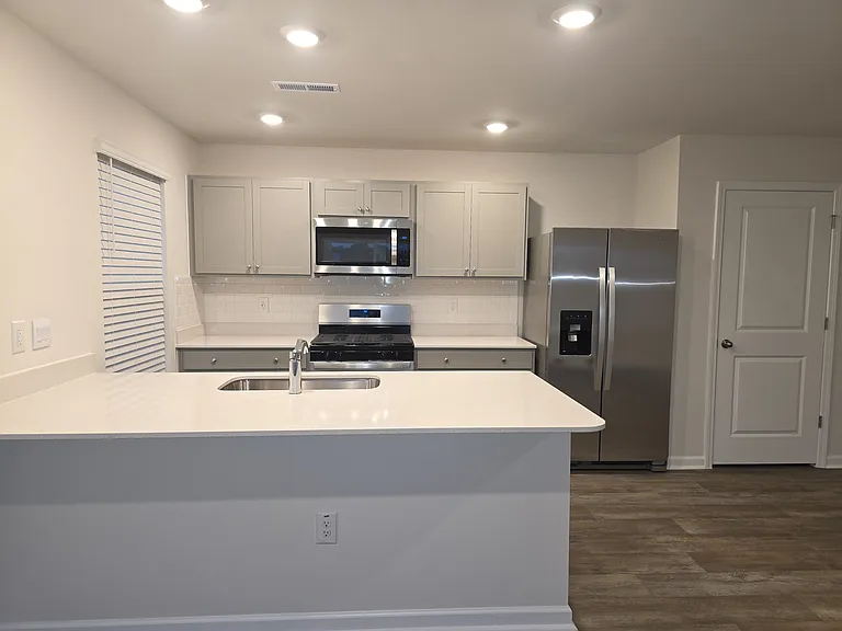 Full kitchen with a pantry and an island. Stainless steel appliances include gas range, microwave, dishwasher, and a double-sided refrigerator with freezer compartment, water dispenser and ice maker.