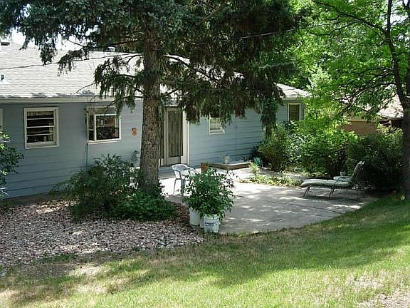 Large patio with mature landscaping offering privacy and shade.