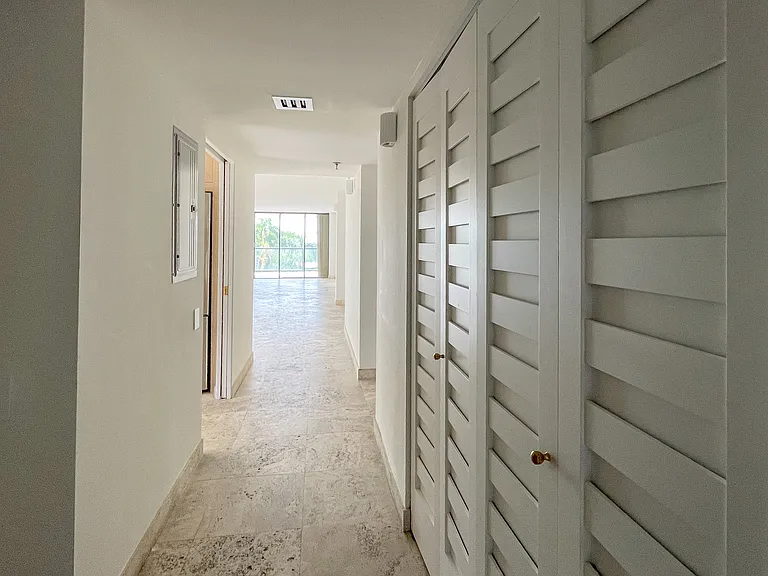 Entryway with kitchen on the left, guest bedroom and bathroom on the right and dining and living room ahead.