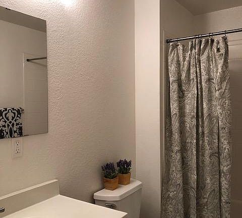 Spacious bath with white faux marble tile floor, white subway tile tub surround, maple shaker vanity