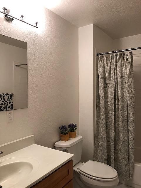Spacious bath with white faux marble tile floor, white subway tile tub surround, maple shaker vanity