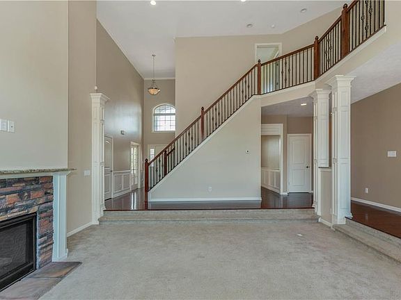 2 story entry leads to 2 story great room with wrought iron stair railing and fireplace