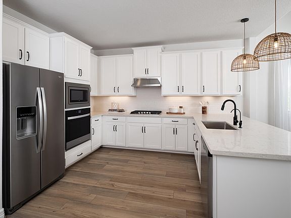 This light and bright kitchen features a large quartz island, white cabinets, a large sink overlooki