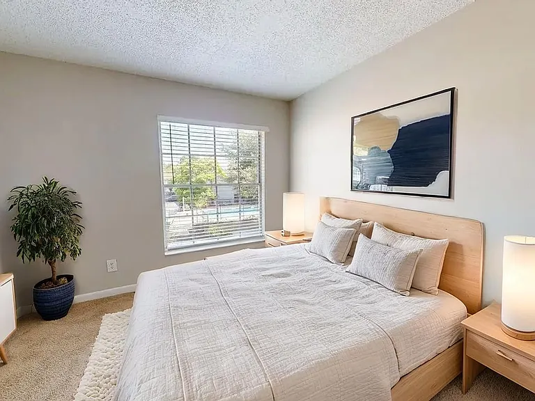 Bright and cozy bedroom with large window, modern decor, and plush bedding, offering a serene and inviting retreat. Bright and cozy bedroom with large window, modern decor, and plush bedding, offering a serene and inviting retreat.