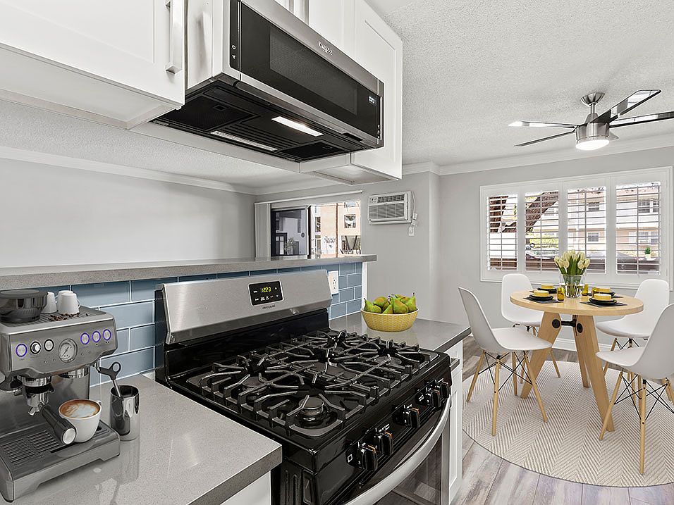 Blue tiled kitchen with stainless steel oven and microwave and view of hardwood floor dining room.