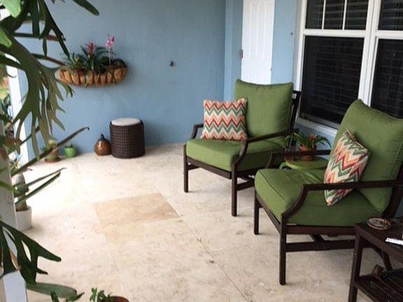 Deep, covered front porch has travertine tile and is a great shady spot to read, relax, or enjoy a rainy evening outside.