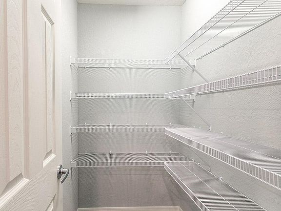 Walk-in pantry with tight mesh shelving - Photo showcases a home with similar finishes. Colors and d