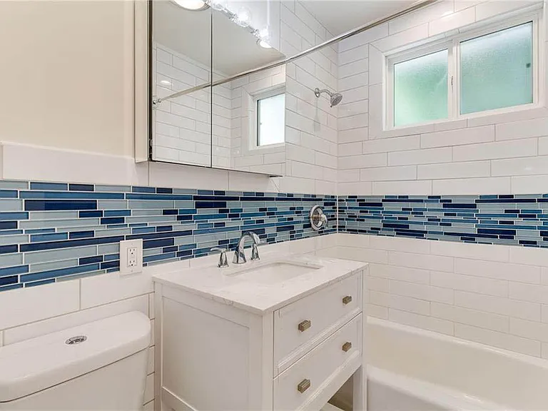 Updated bathroom with white shaker vanity, subway tile and coastal inspired tile inlay