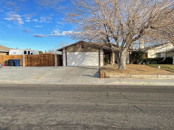 Front view of home; winter season when tree has shed all leaves.
Large driveway, fenced yard.