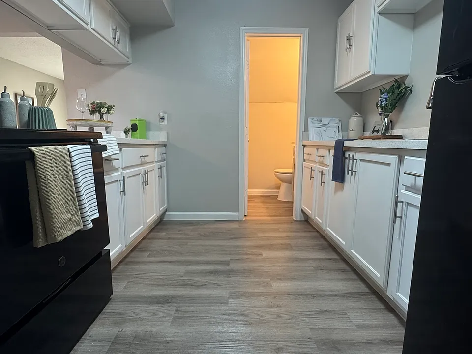 This updated galley_style kitchen offers sleek white cabinetry, modern appliances, and a spacious, well_lit layout with convenient access to the nearby bathroom.