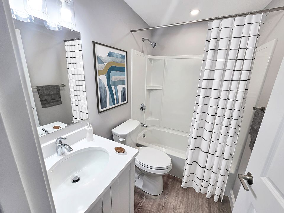 Modern bathroom with elegant fixtures, stylish artwork, and a chic white shower curtain, showcasing a pristine and inviting ambiance.
