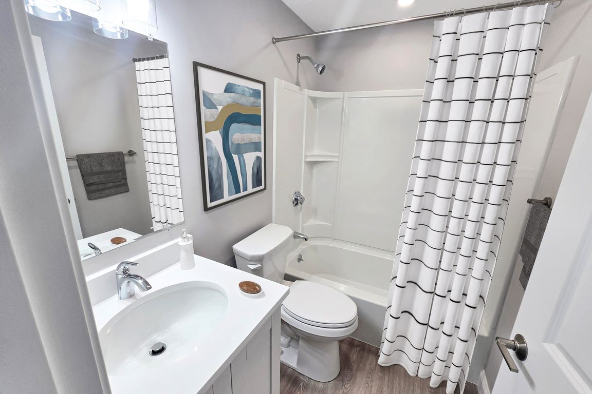 Modern bathroom with elegant fixtures, stylish artwork, and a chic white shower curtain, showcasing a pristine and inviting ambiance.