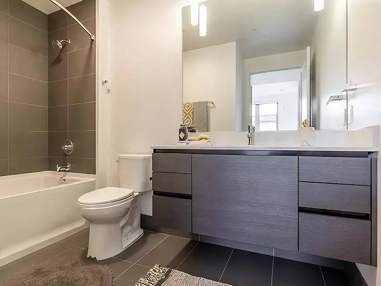 Apartment Bathroom with Tub, Large Mirror, and Dual Sink Vanity