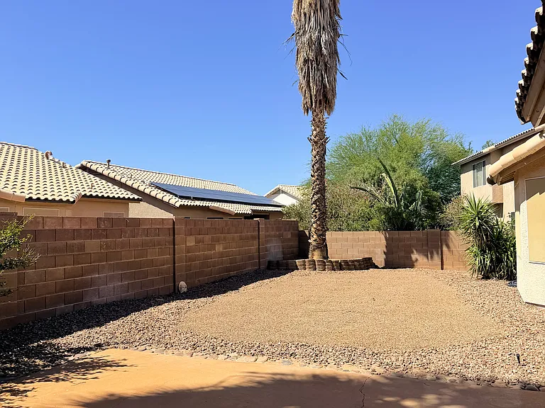 outdoor patio with river rock and pea gravel landscaping surrounded by palm trees