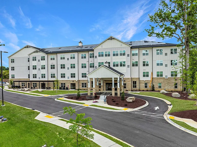 Active Adult Community with an exterior view of an apartment building with a courtyard and benches