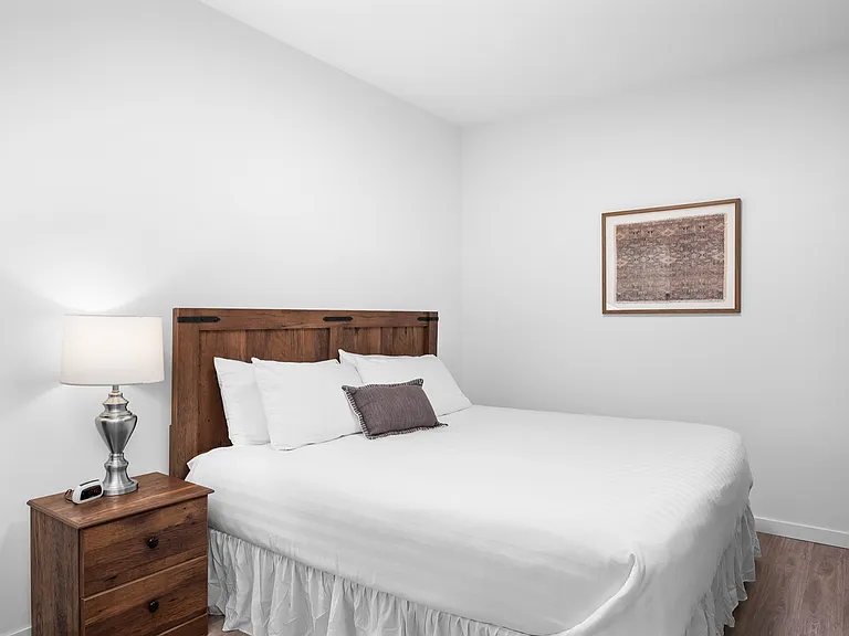 Cozy bedroom with a stylish wooden headboard, crisp white bedding, and an elegant bedside lamp creating a warm ambiance. Cozy bedroom with a stylish wooden headboard, crisp white bedding, and an elegant bedside lamp creating a warm ambiance.